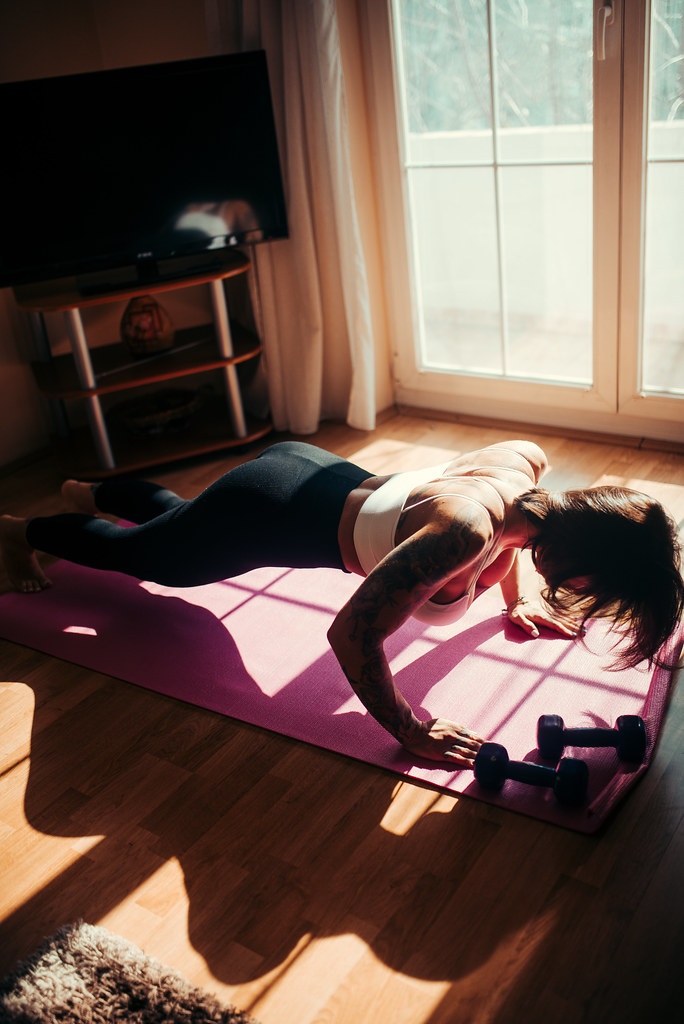 Tattooed young women exercise indoor at home she is acted home gym photo