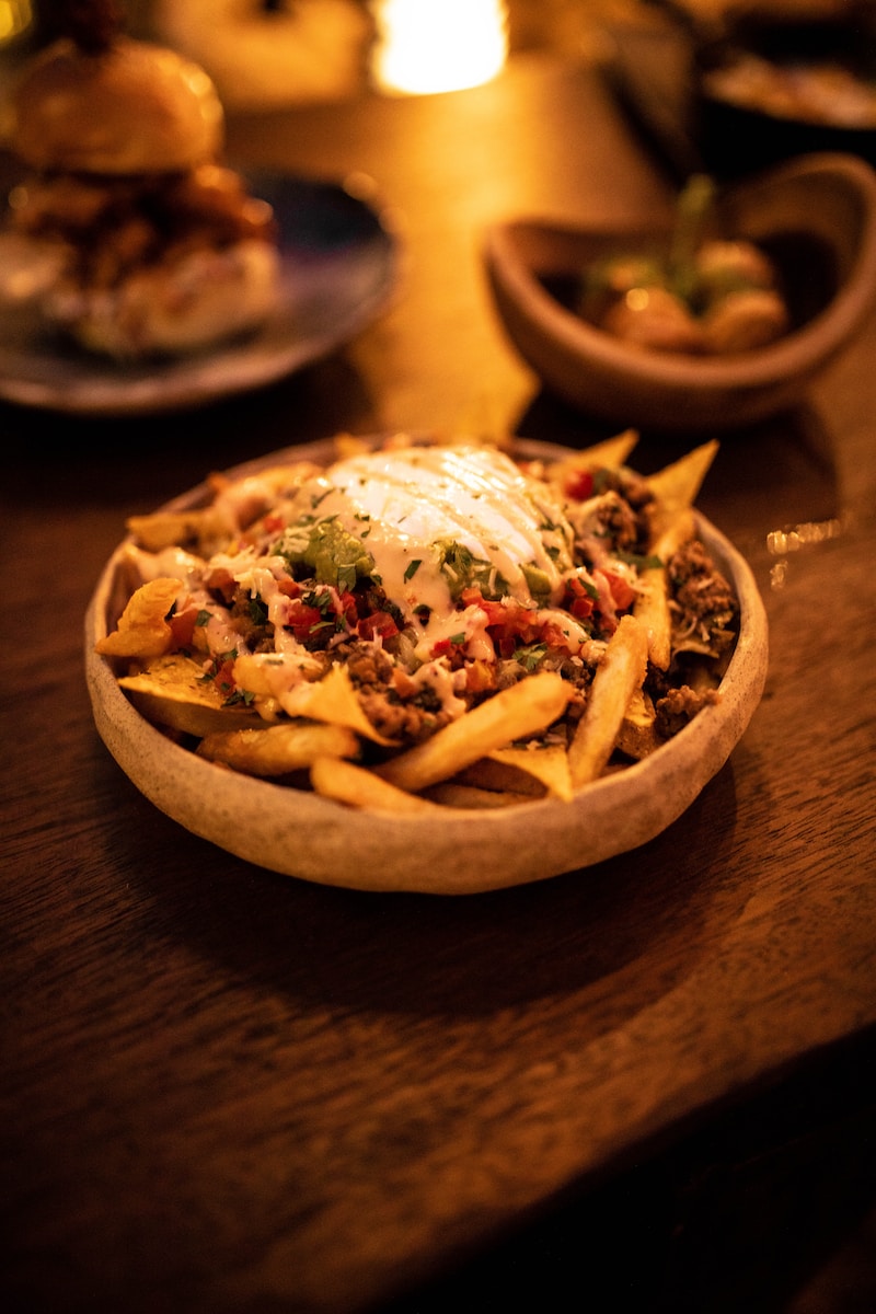 a wooden table topped with a bowl of fries