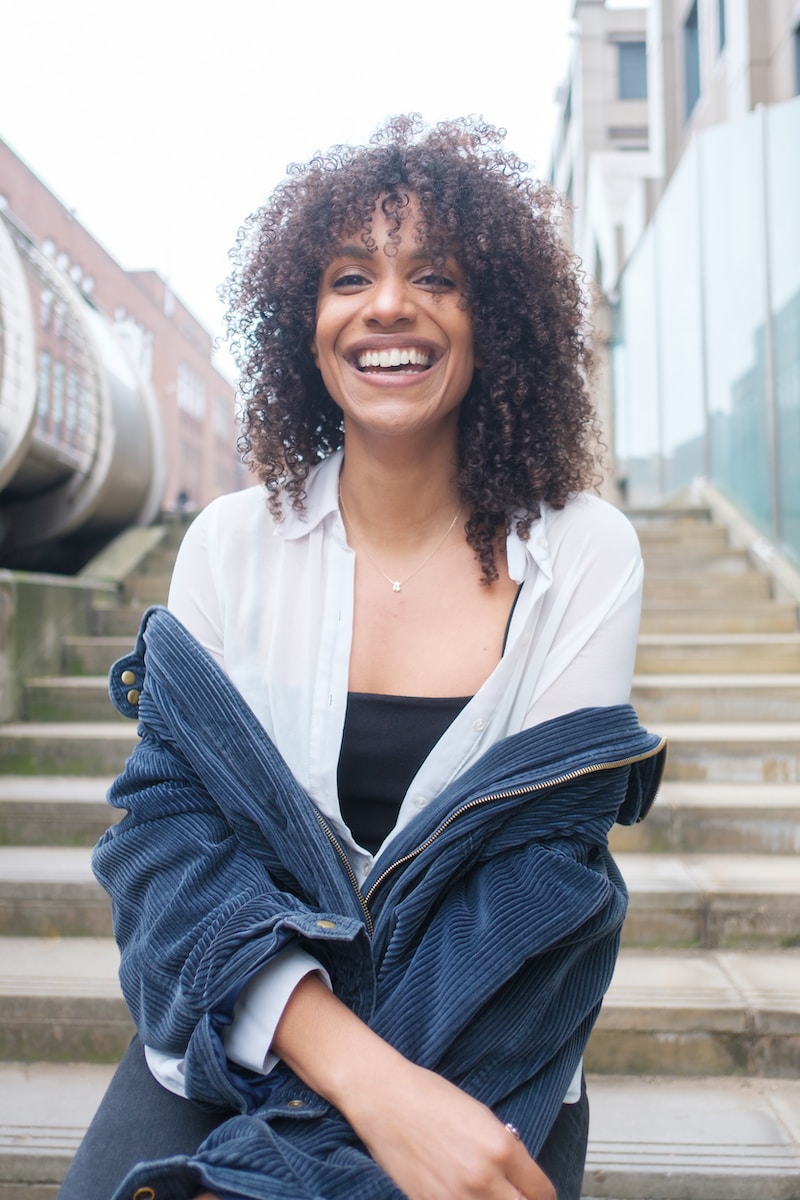 a smiling woman sitting on the steps of a building