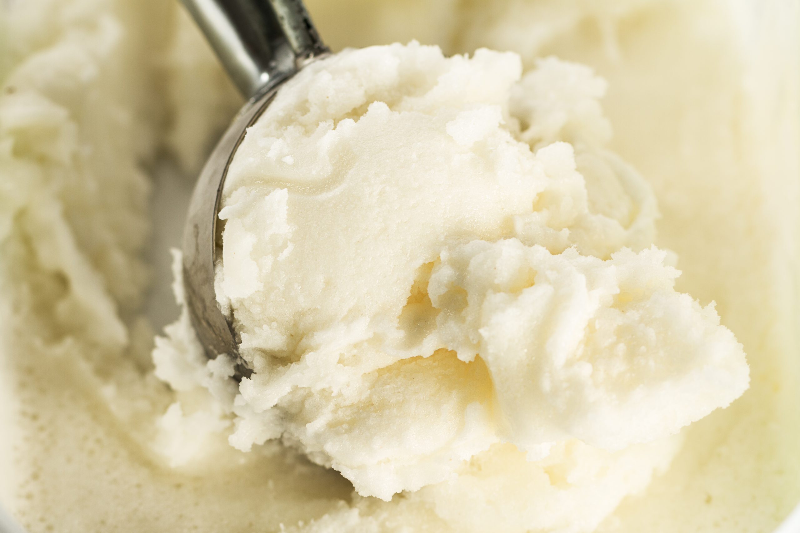 tasty appetizing pure vanilla creamy ice cream with ice cream spoon closeup horizontal with copy space scaled