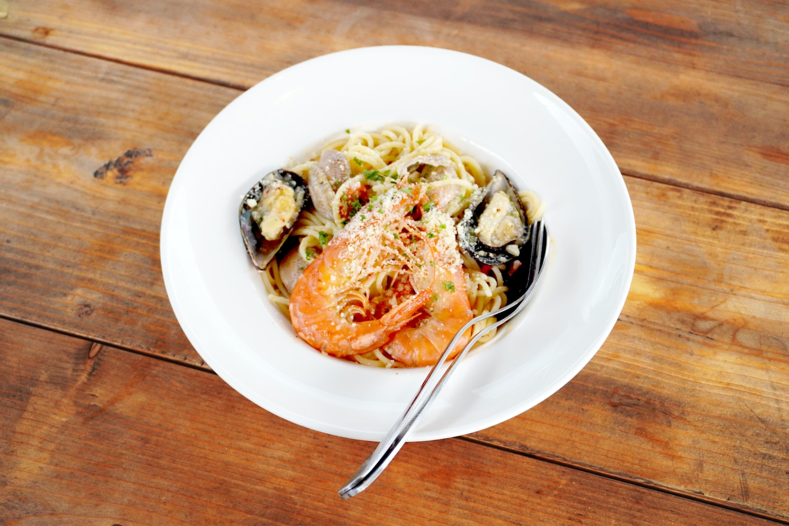 a plate of pasta with shrimp, mussels and parmesan cheese