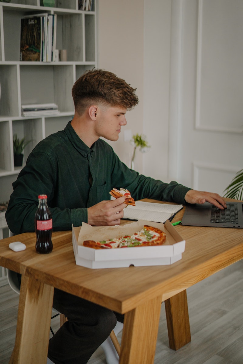 Man Eating Pizza and Working From Home
