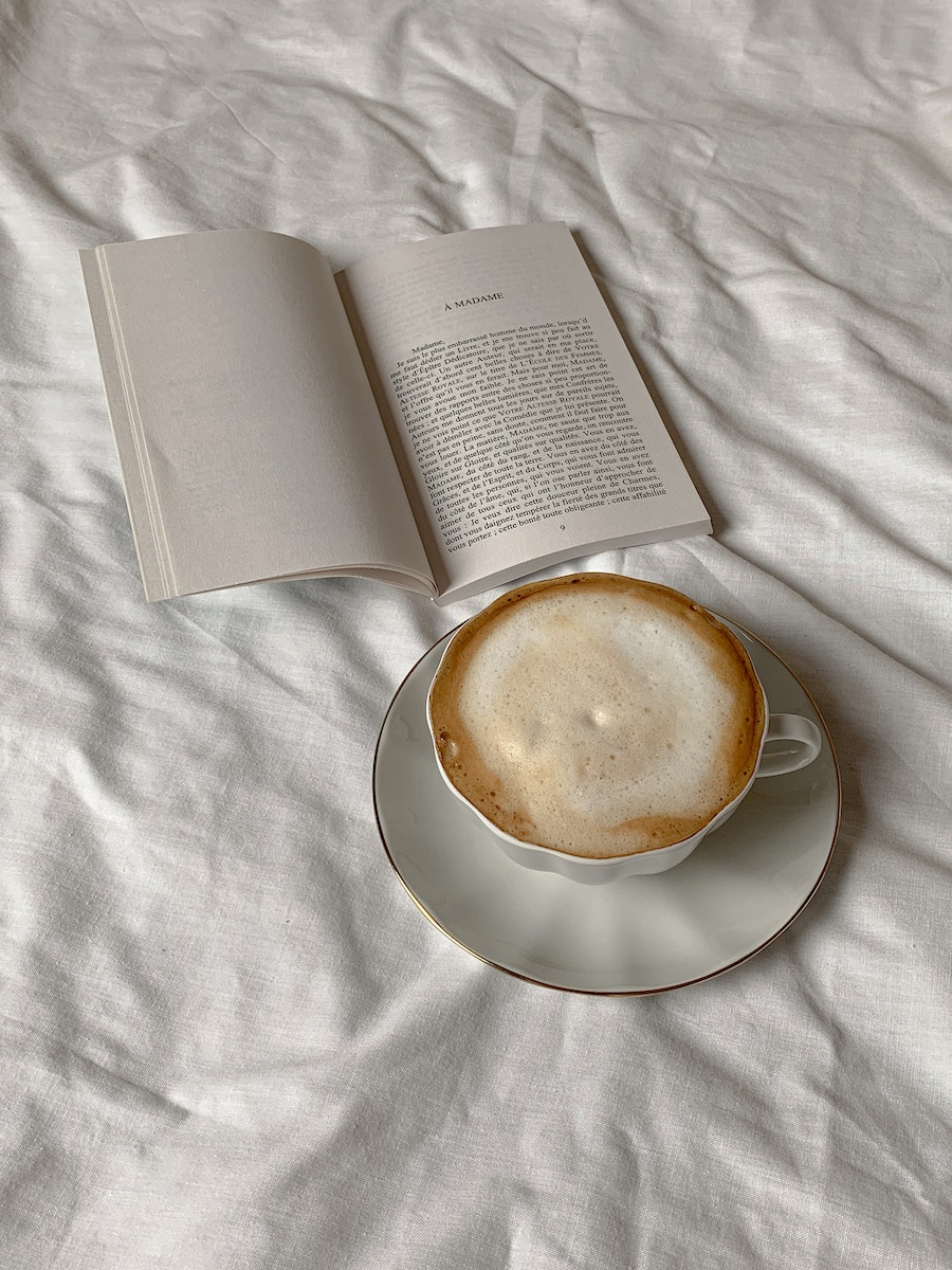 Close-Up Shot of a Cup of Cappuccino beside a Book