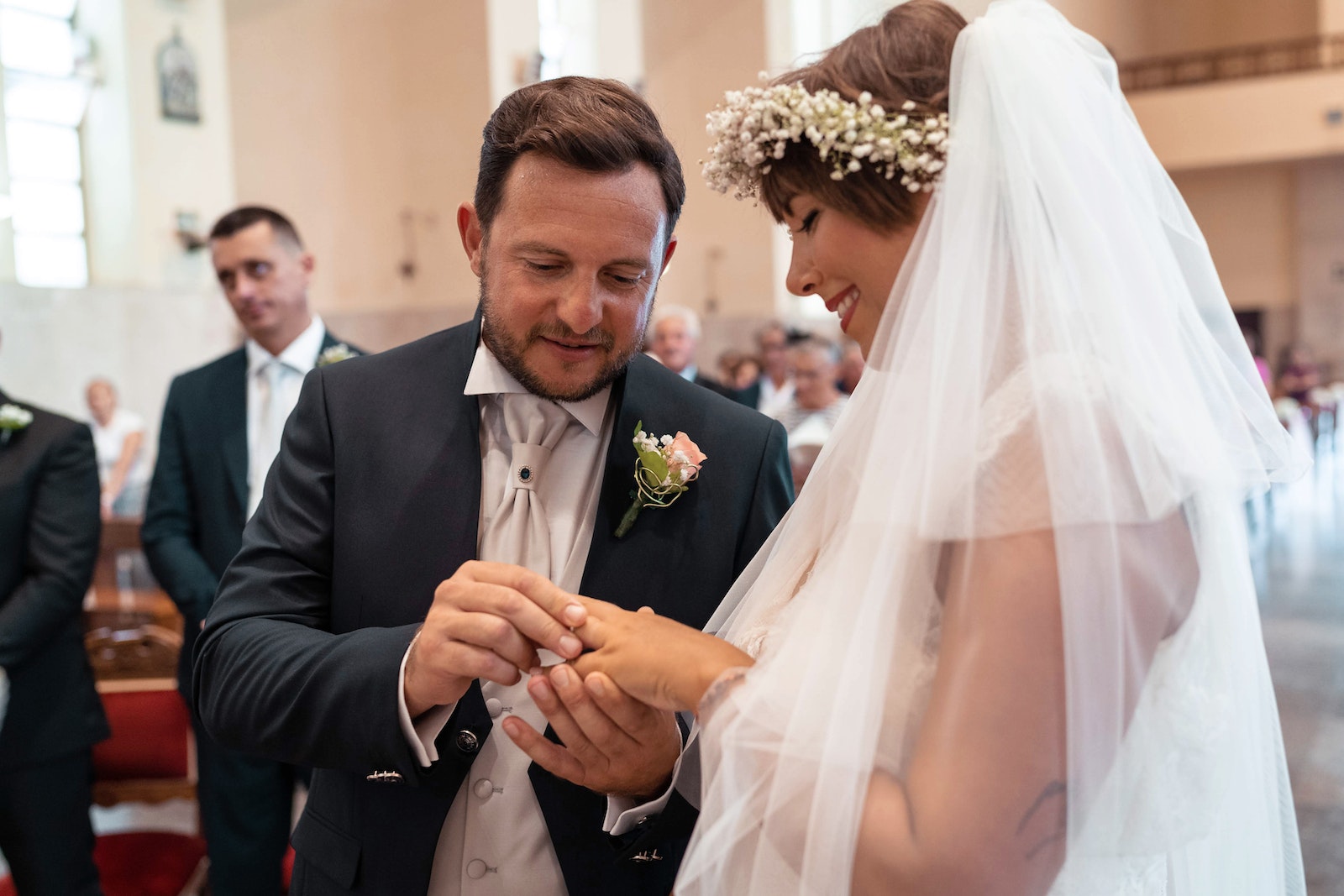 Happy groom putting ring on brides finger