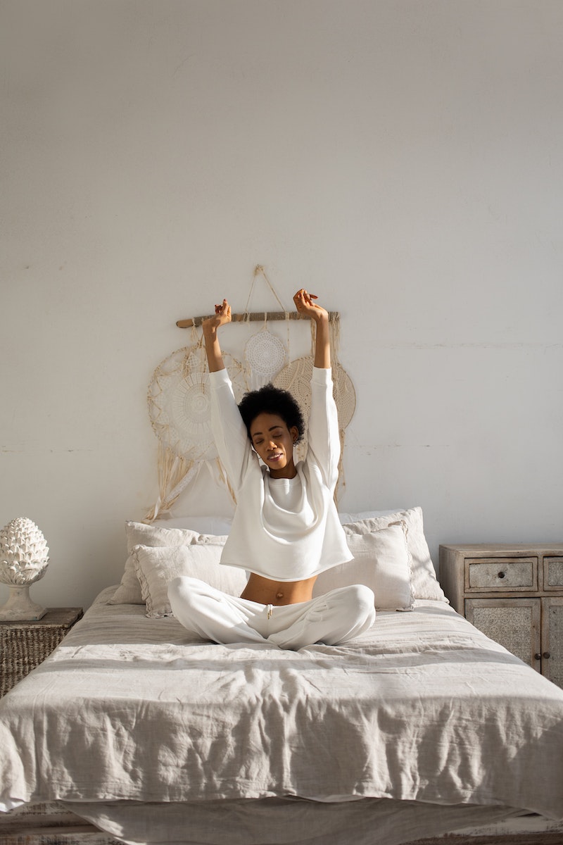 A Woman in White Long Sleeves Sitting on the Bed
