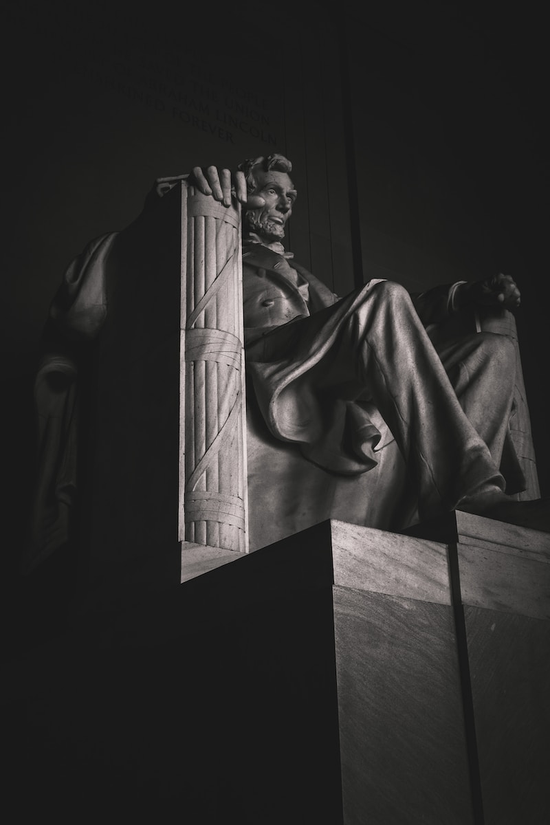 man in robe statue in grayscale photography