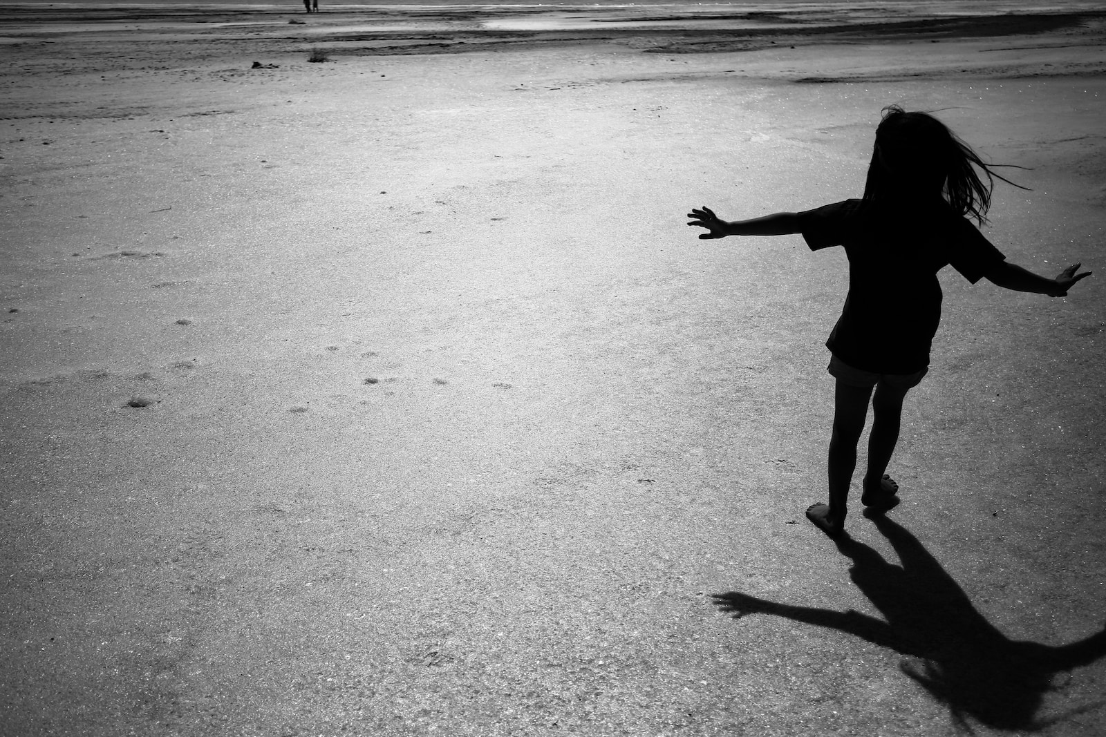 a little girl running across a sandy beach