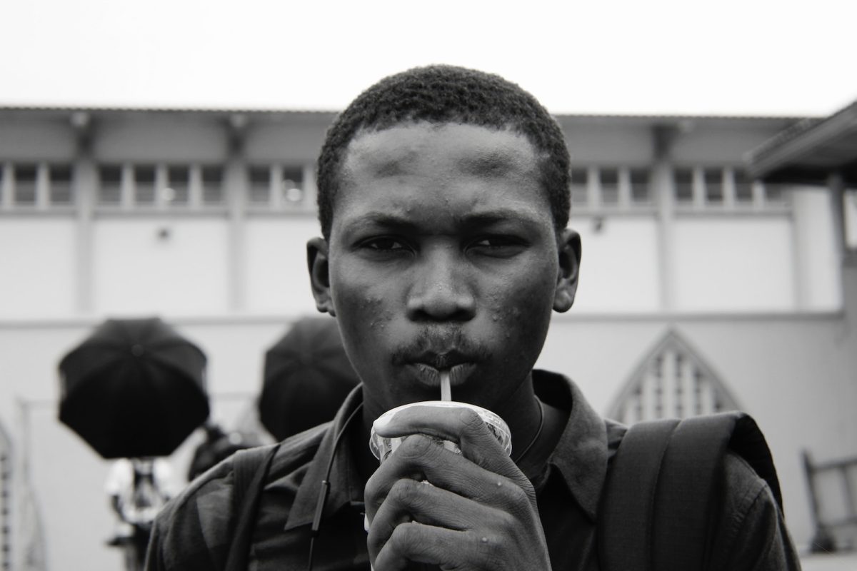 grayscale photography of man sipping on straw