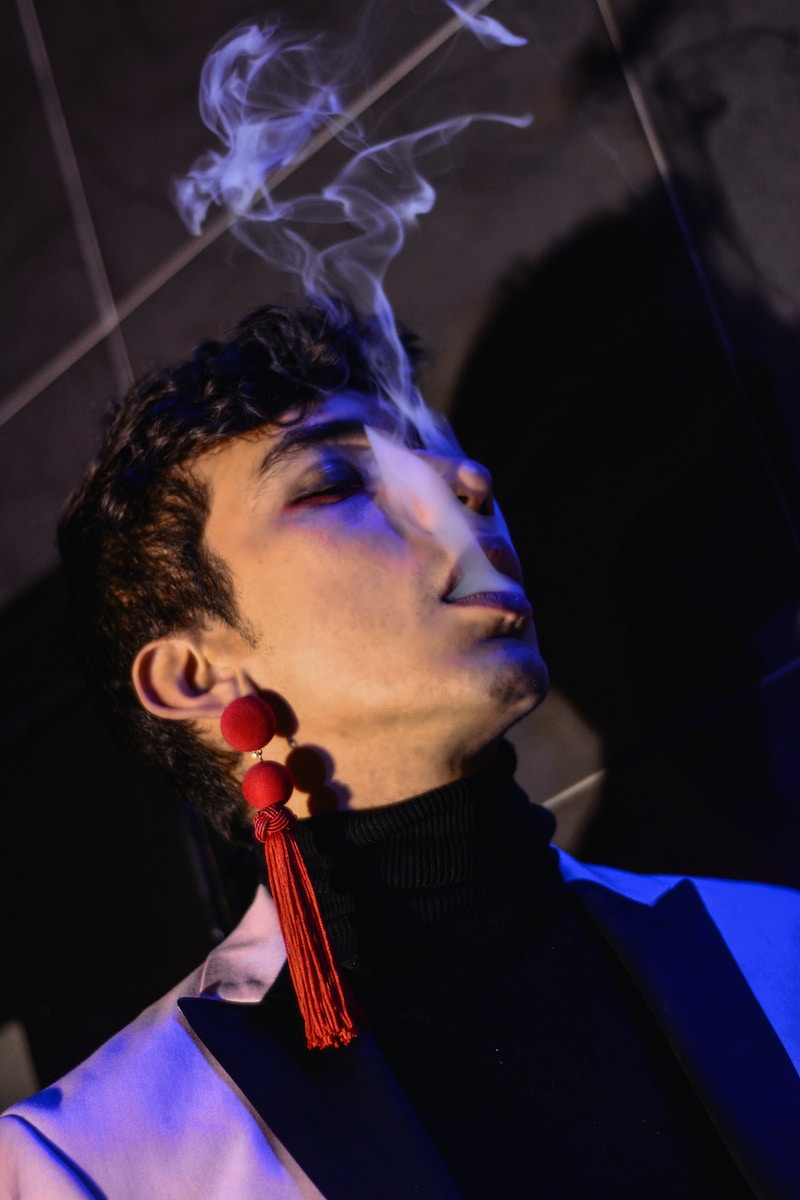 a man smoking a cigarette in a dark room