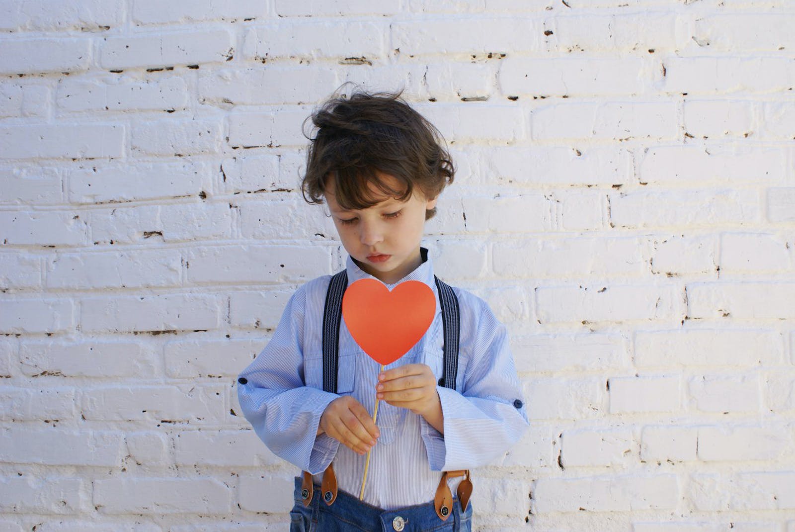 Photo of Boy Holding Heart-shape Paper on Stick
