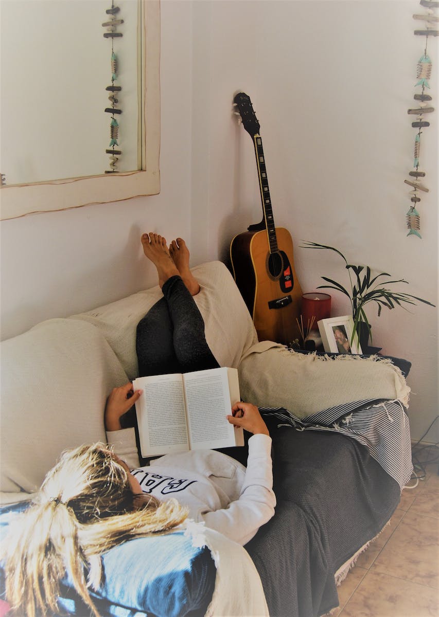 Woman Reading Book While Lying On Sofa