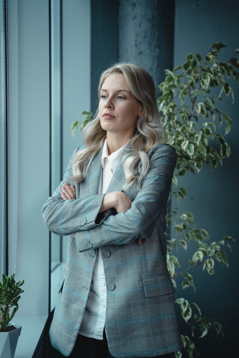 Woman in Gray Blazer Standing Near Green Plant With A Serious Look