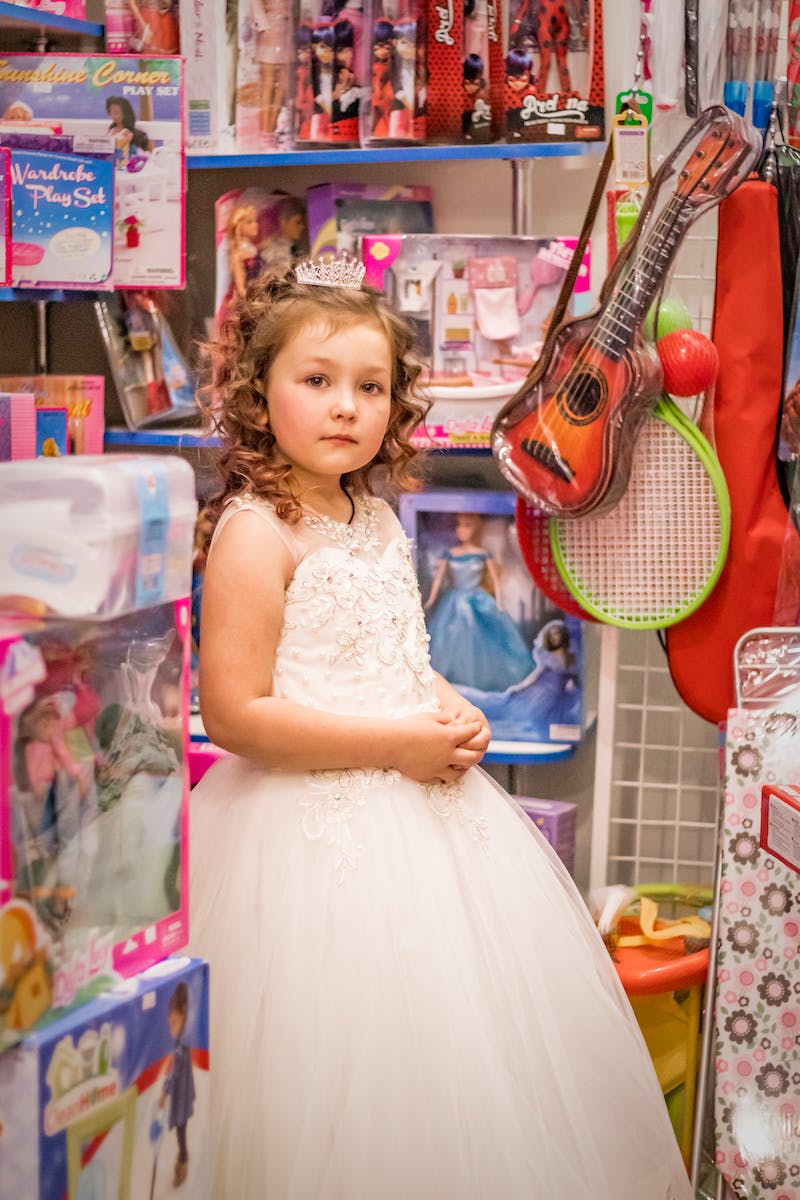 Girl in White Gown Standing Near Toys