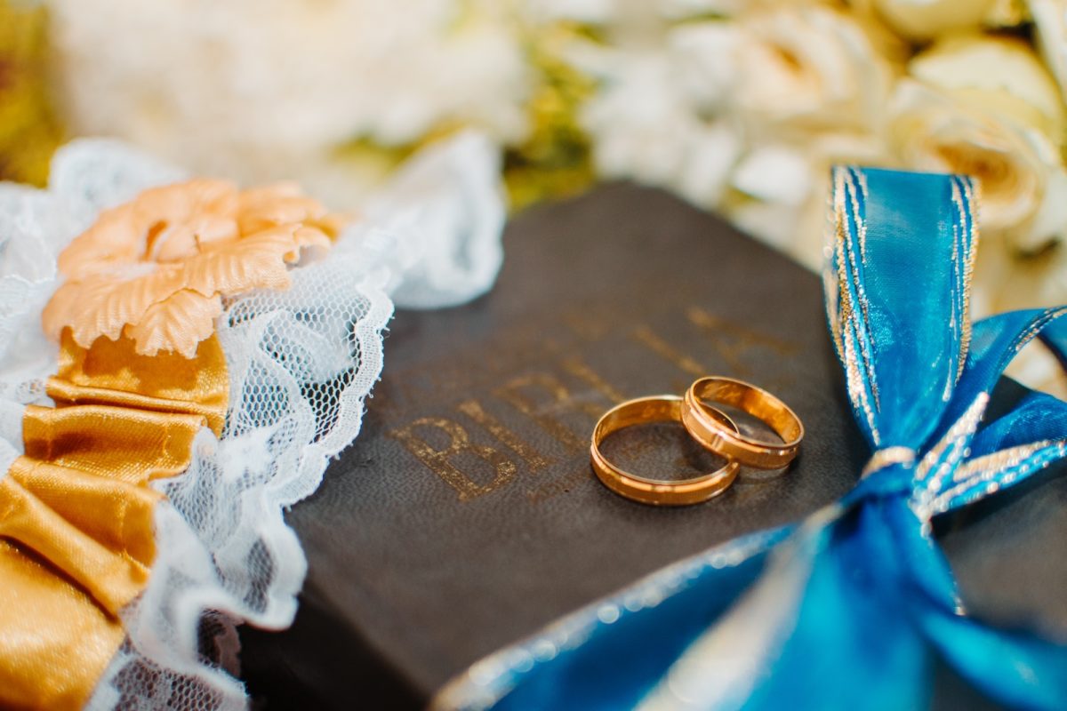 gold-colored wedding rings on Bible scripture