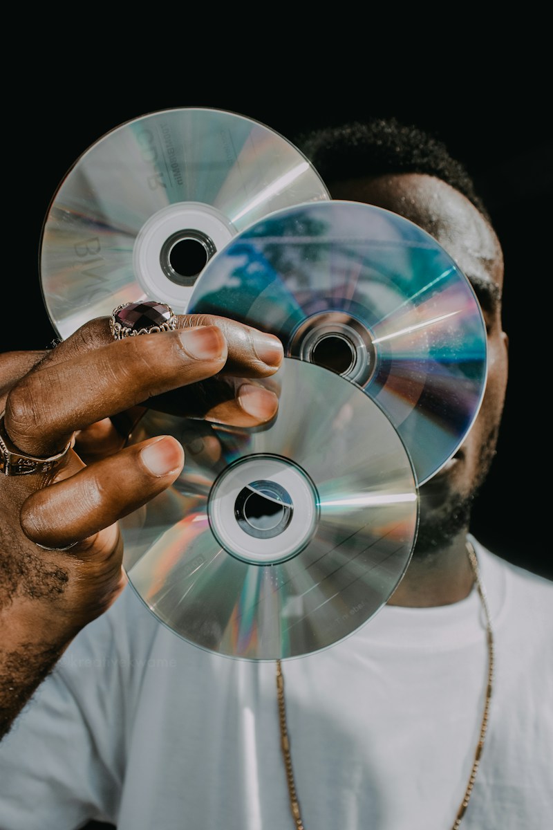 a man holding three cds in front of his face