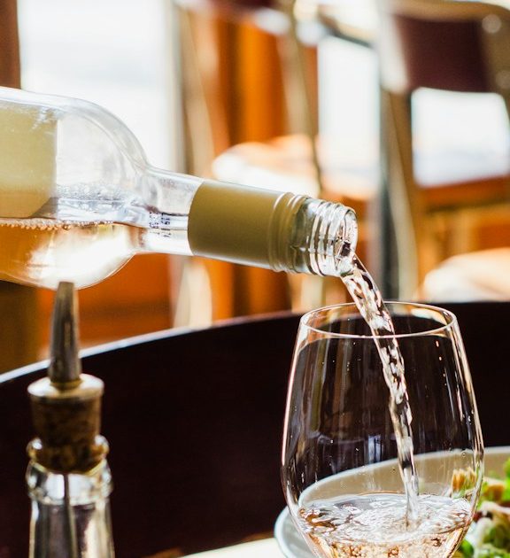 person pouring wine in wine glass