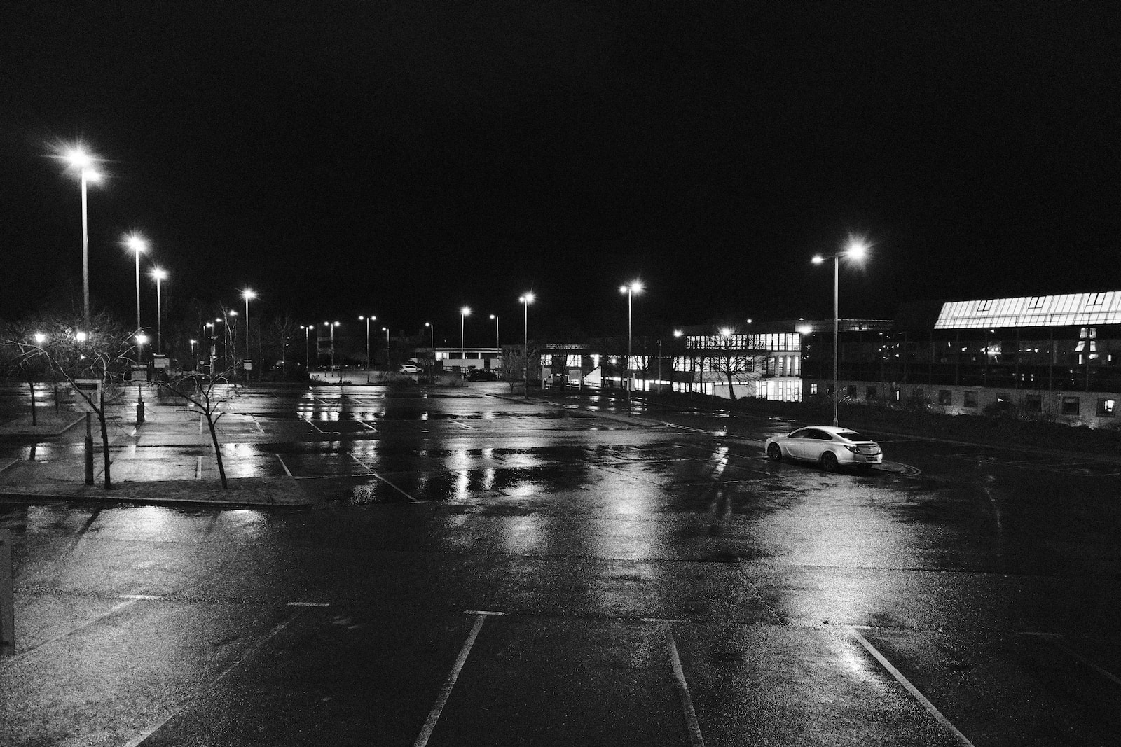 a black and white photo of a parking lot at night