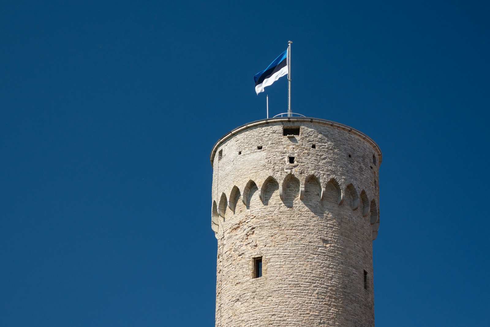 brown concrete tower with blue, black, and white flag on top