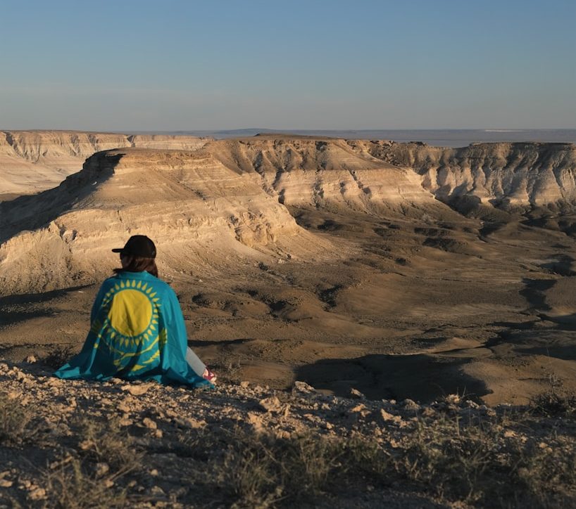 woman in blue and green jacket standing on brown rock formation during daytime