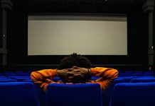 a person sitting in a chair in front of a projection screen