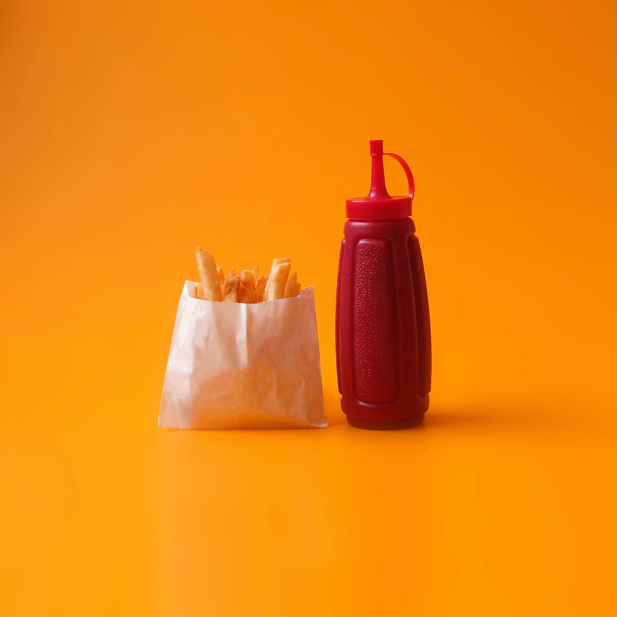 fried fries in white pack beside red squeeze bottle