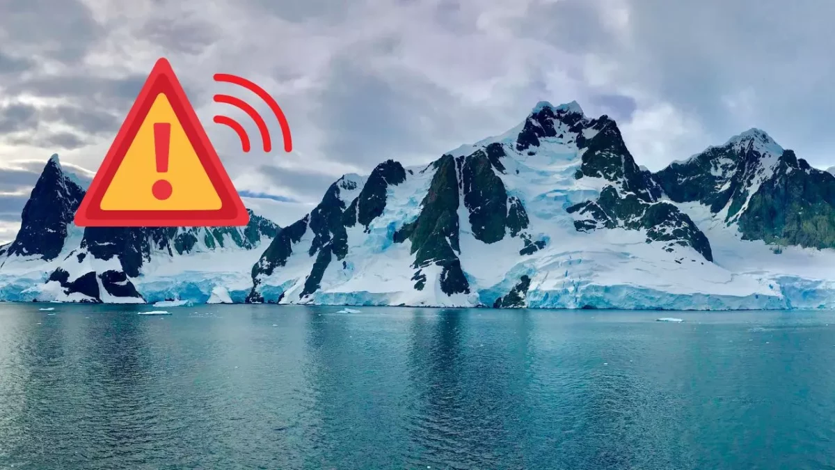 Upozornenie na klimatické zmeny: Zasnežené hory na Antarktíde s varovnou ikonou v popredí.