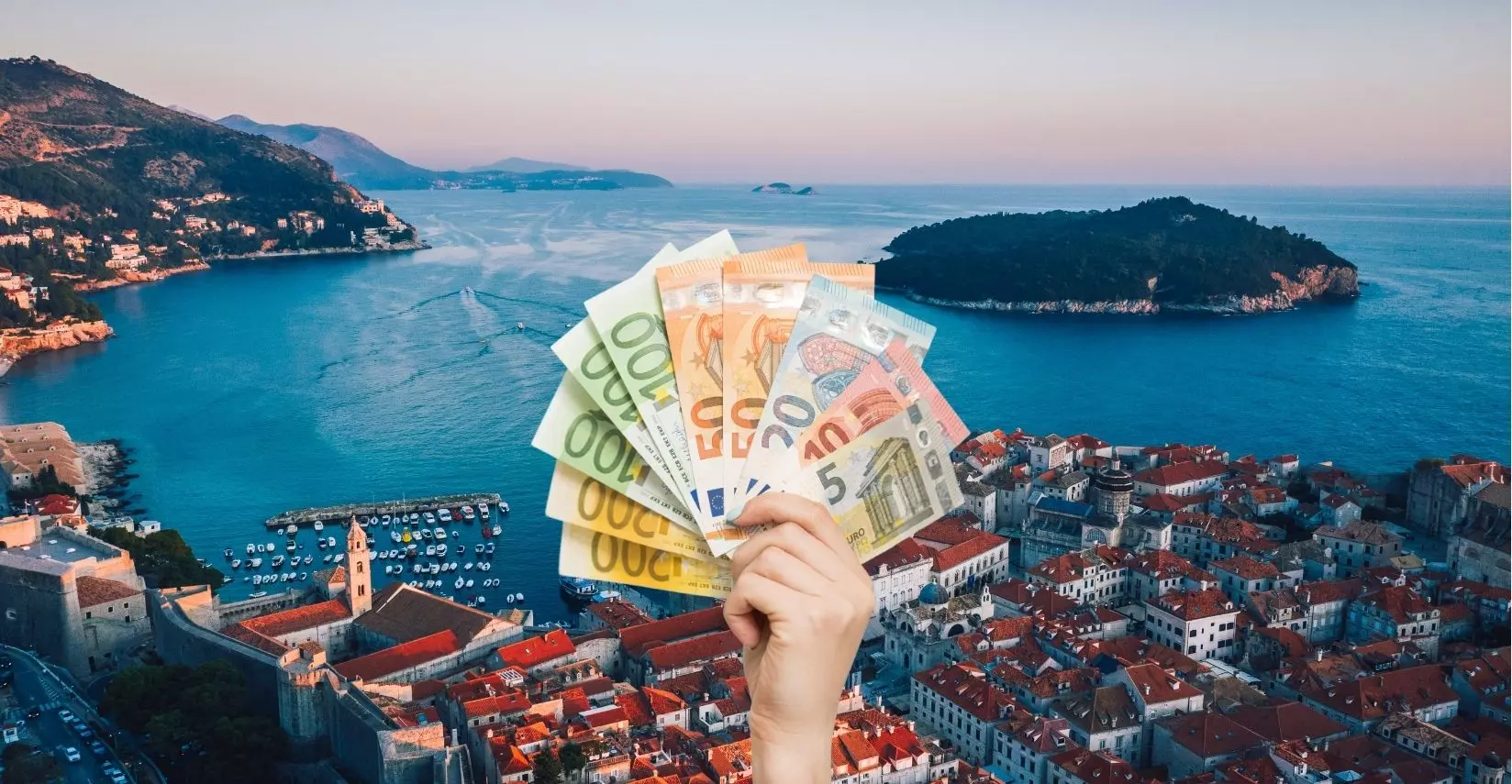 Ruka držiaca eurá na pozadí pobrežného mesta v Chorvátsku pri západe slnka, symbolizuje cestovanie a financie.