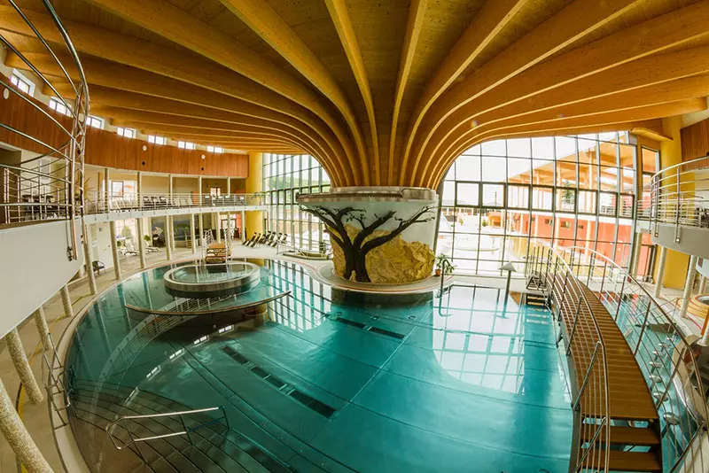 Moderné wellness centrum s bazénom a unikátnym dreveným stropom pre relax a oddych посетителей.