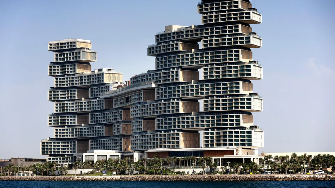 Moderný vrstvený hotel s unikátnym dizajnom v Dubaji pri mori pod modrou oblohou.