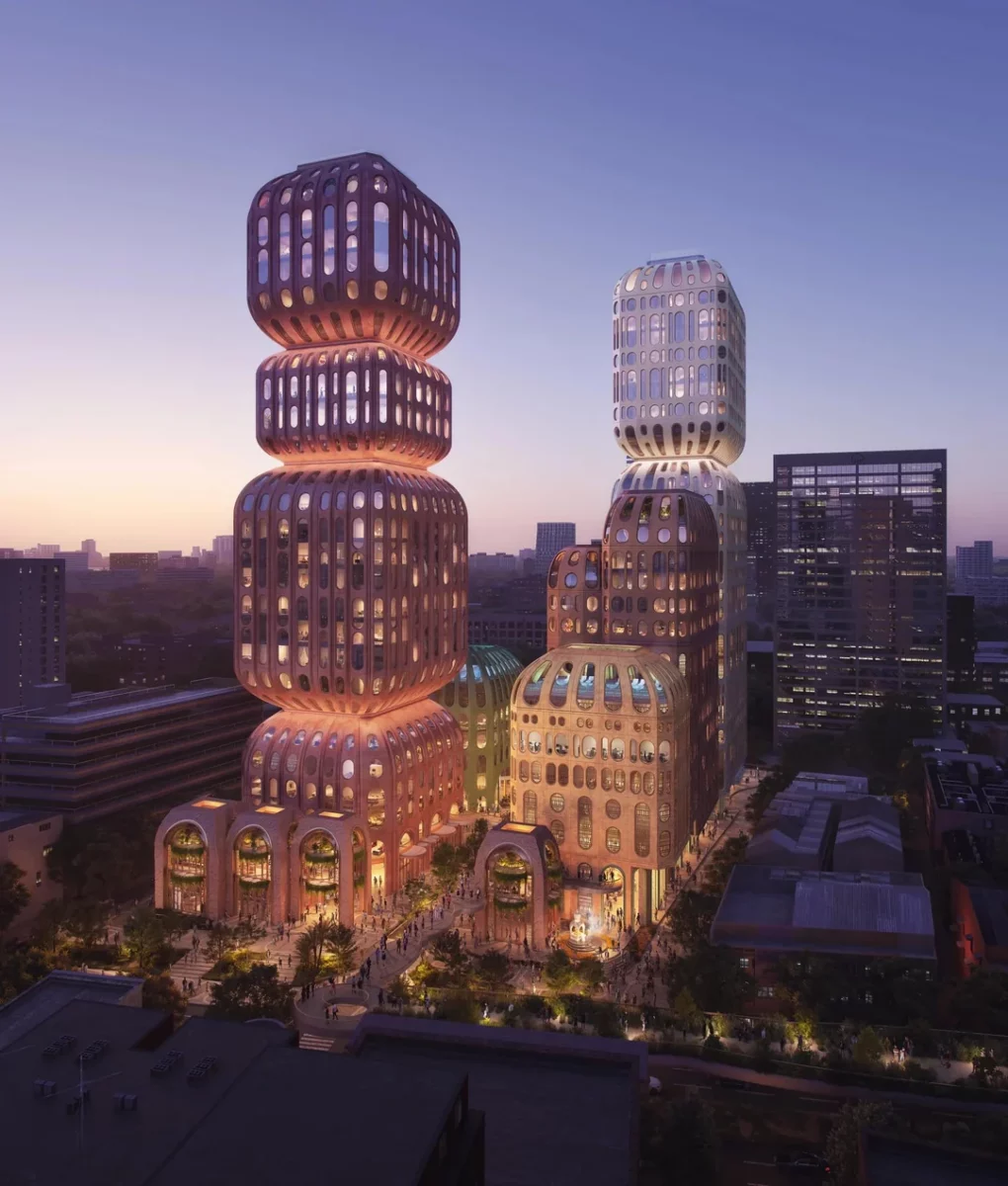 Moderné mrakodrapy so zaoblenou architektúrou pri západe slnka, osvetlené a obklopené mestskou scenériou.