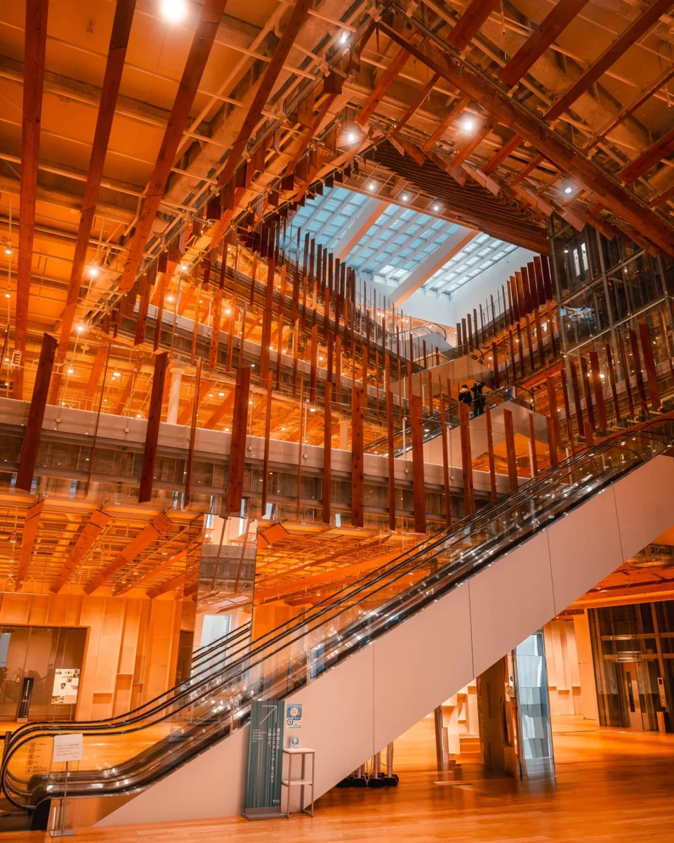 Moderný interiér so schodiskom a drevenými konštrukciami osvetlený teplým svetlom v architektonicky odvážnej budove.