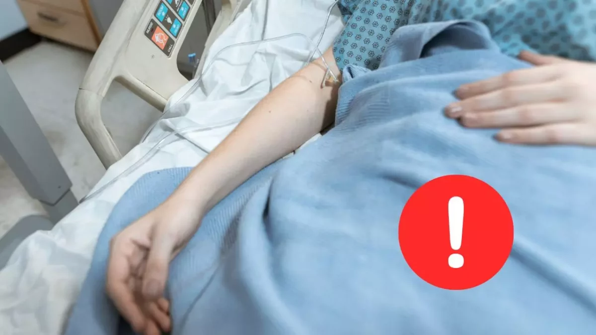 Pacient s infúziou leží v nemocničnej posteli, zvýraznený červený výstražný symbol.
