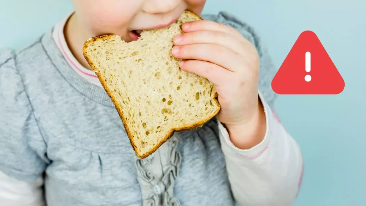 Dieťa s chlebom pri označení varovania, modré pozadie. Pozor na potravinové alergie.