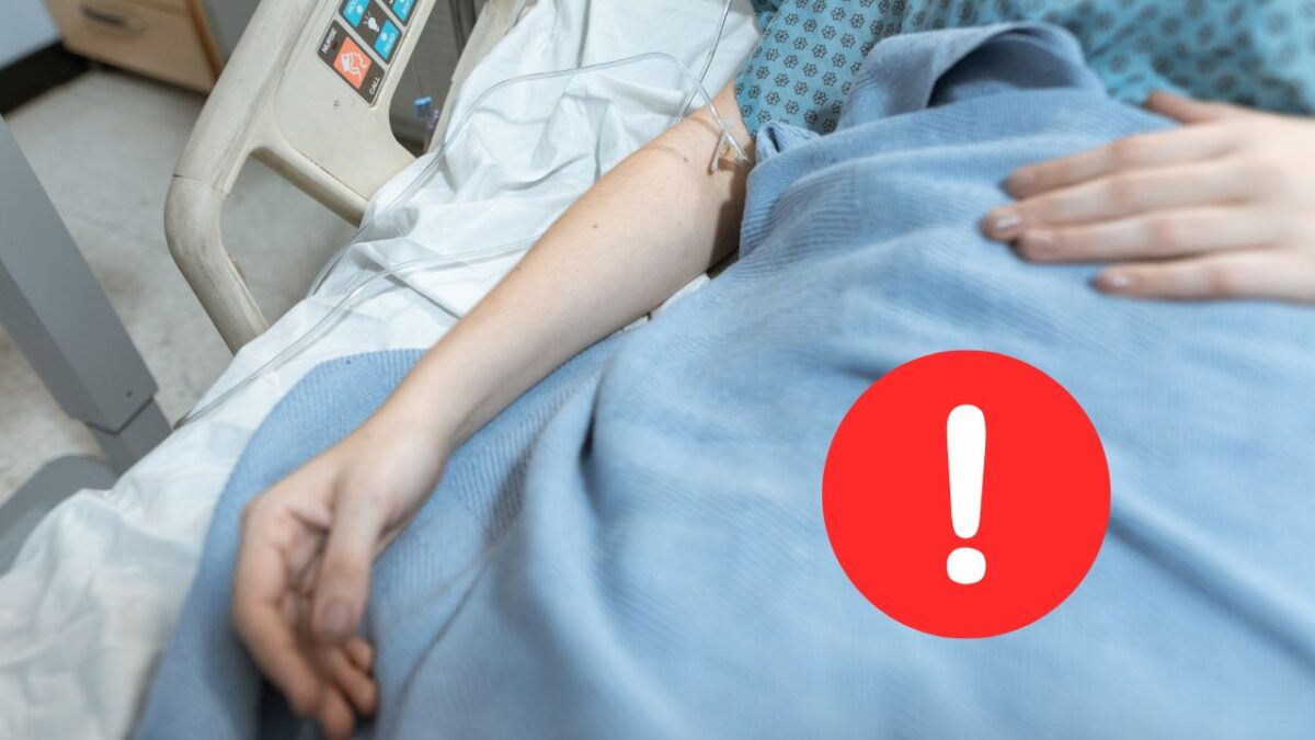 Pacient ležiaci v nemocničnej posteli s infúziou, červená výstraha na rýchlu lekársku starostlivosť.