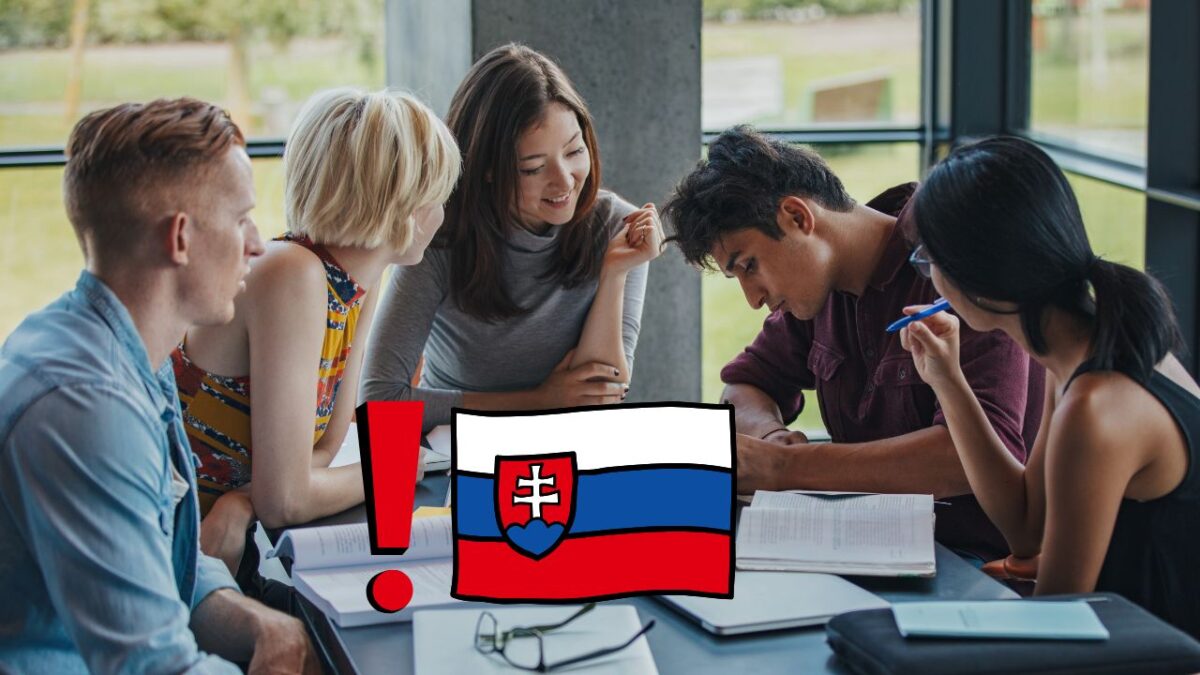 Skupina študentov spolu študuje pri stole so slovenskou vlajkou v popredí.