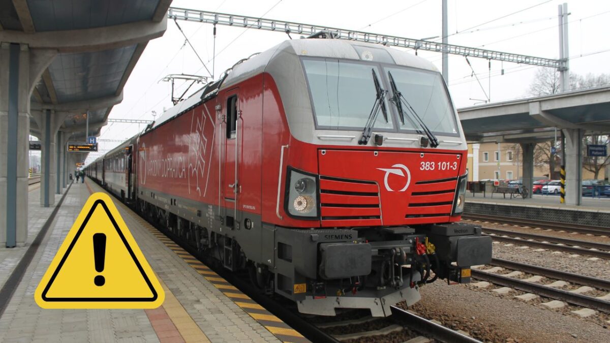 Červená vlaková lokomotíva na stanici pripravená na odchod. Pozor na výstražnú značku!
