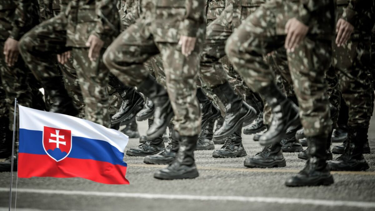 Slovenskí vojaci pochodujú v uniforme, v popredí vlajka Slovenskej republiky.