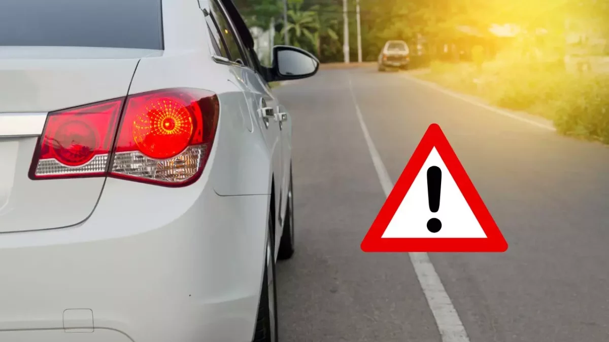 Auto so svietiacim brzdovým svetlom a výstražným trojuholníkom na ceste.