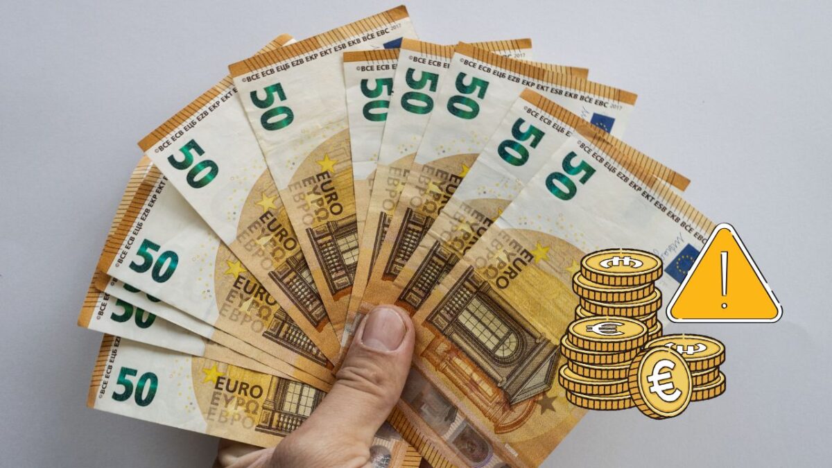 Osoba drží vejárovito rozložené bankovky 50 eur s mincami a výstražným symbolom.
