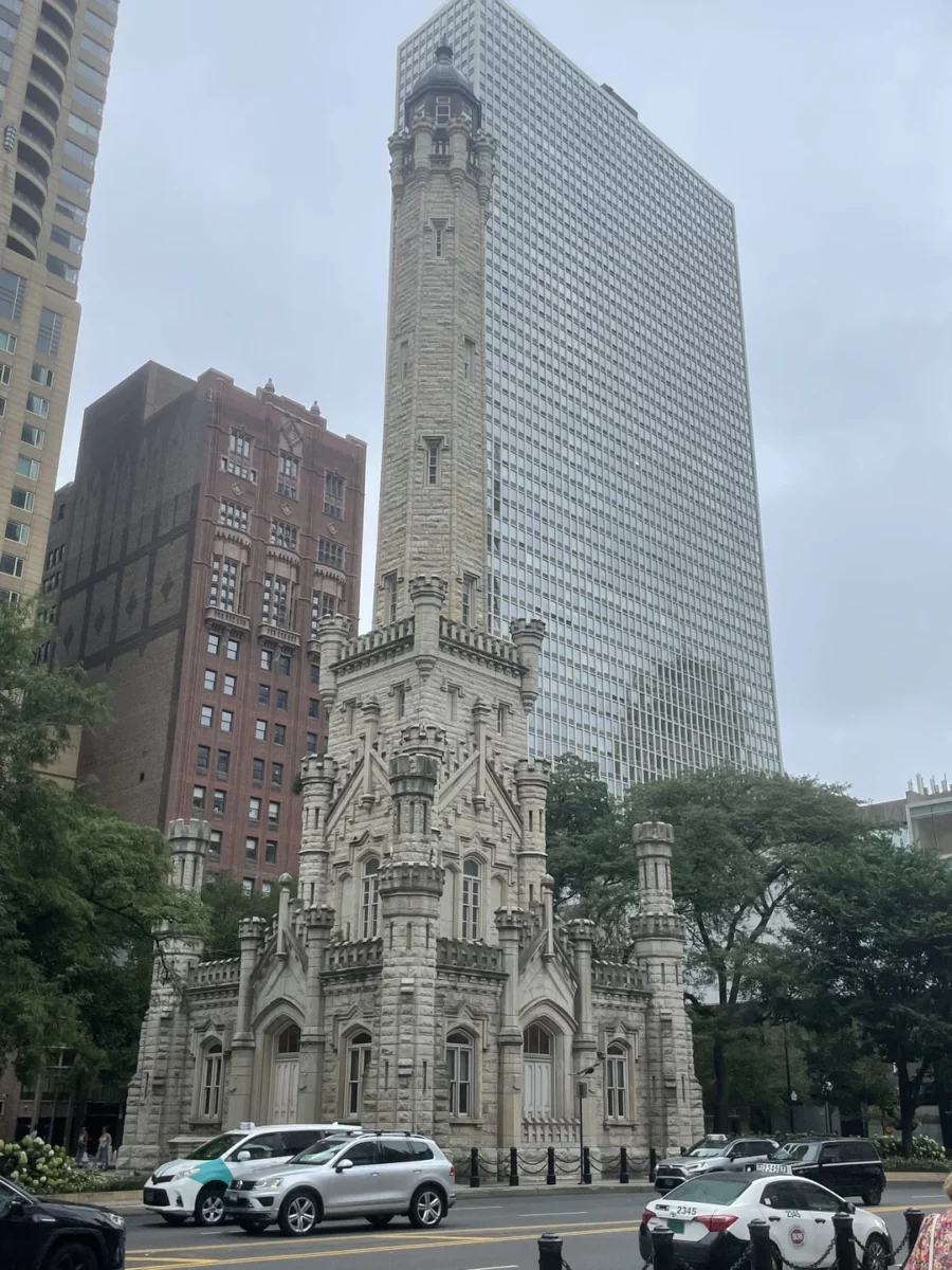 Stará vodná veža v Chicagu pred moderným mrakodrapom s autami na ulici.