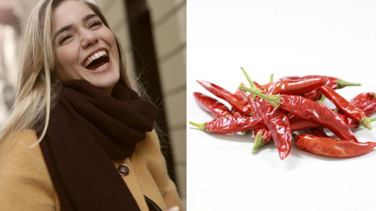 Žena sa smeje vedľa hromady červených chilli papričiek na bielom pozadí.