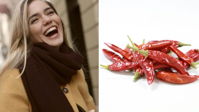 Žena sa smeje vedľa hromady červených chilli papričiek na bielom pozadí.