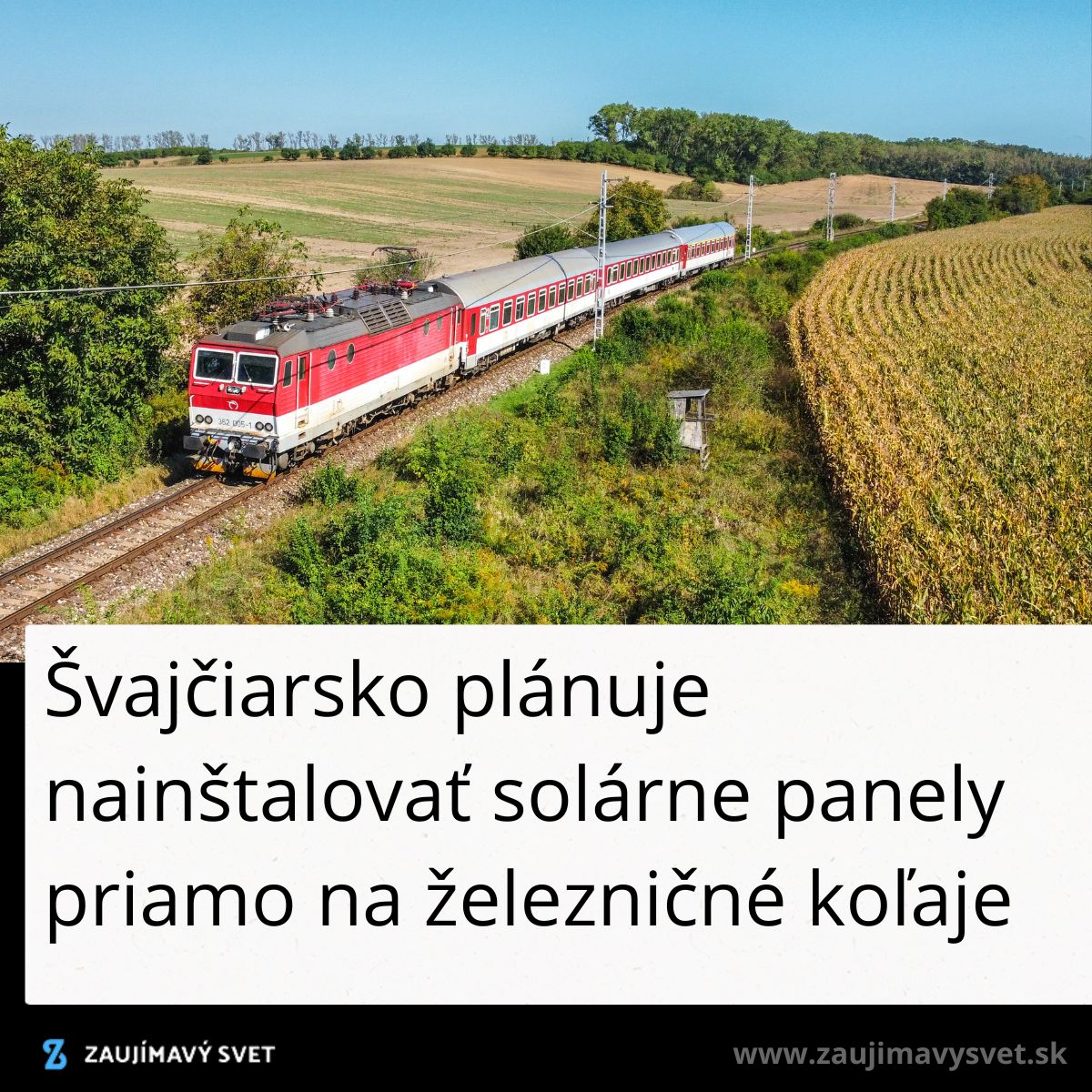 Červený vlak prechádza cez vidiecku krajinu s poľami a zeleňou, za slnečného dňa.