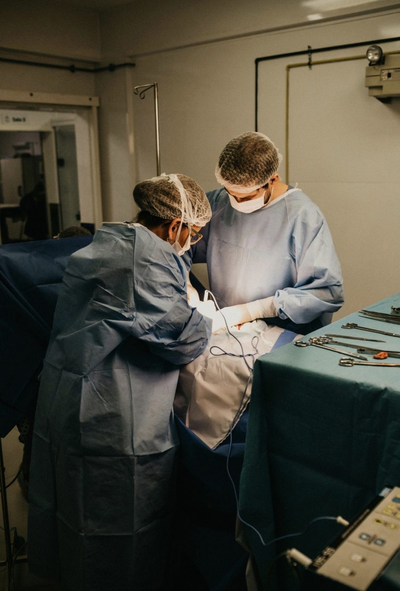 Chirurgovia v operačnej sále pri operácii, oblečení v modrých plášťoch a ochranných maskách.