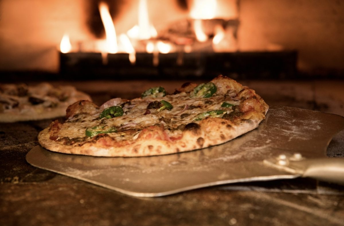 Pizza pečená v tradičnej peci na drevo, chrumkavá kôrka, čerstvé ingrediencie, talianska kuchyňa.