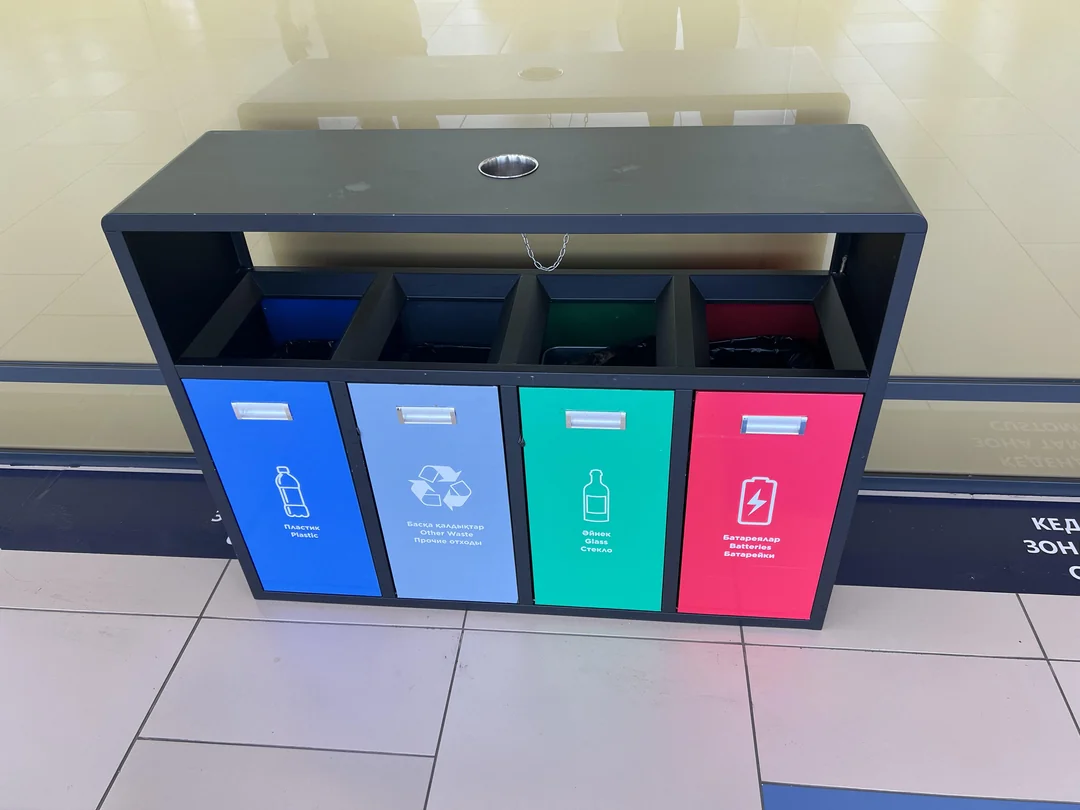 Kontajnery na triedenie odpadu: modrý na plast, sivý na zmiešaný odpad, zelený na sklo, červený na batérie.