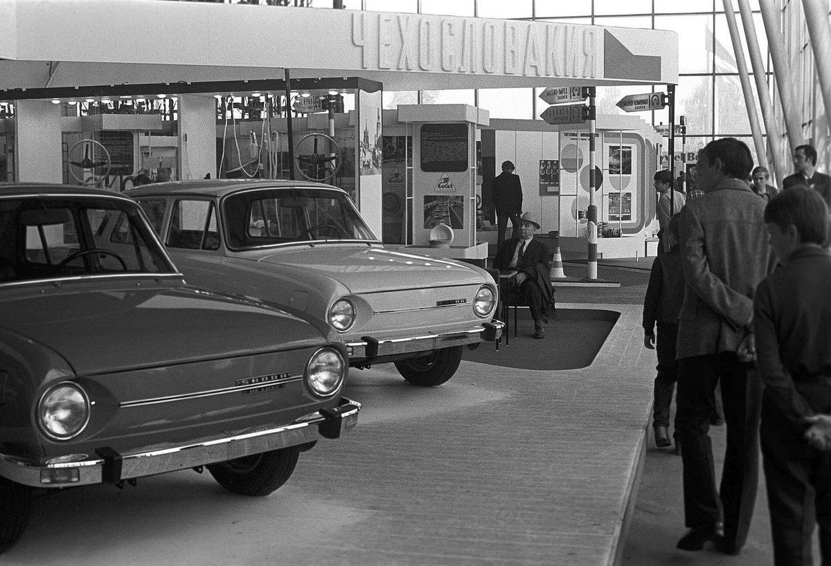Historická výstava s československými autami na autosalóne, ľudia obdivujú vystavené modely.