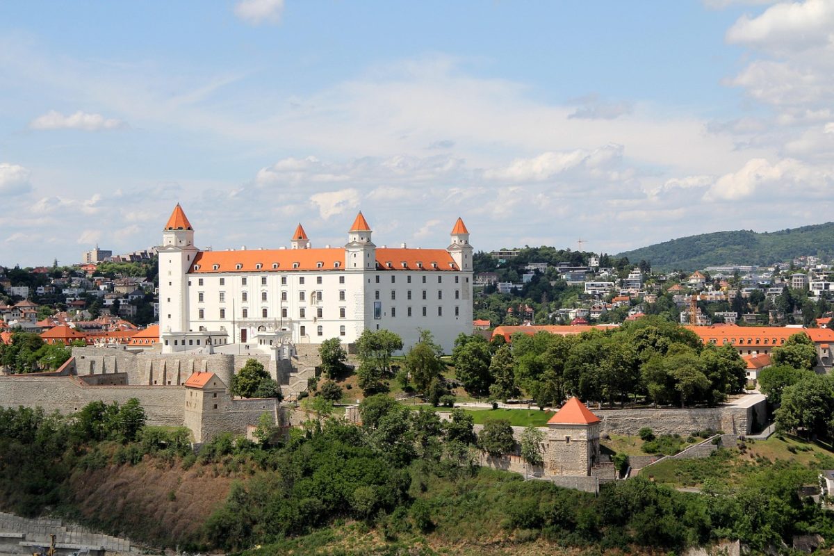 Bratislavský hrad v letnom slnečnom dni, dominanta Bratislavy obklopená historickým mestom a zeleňou.