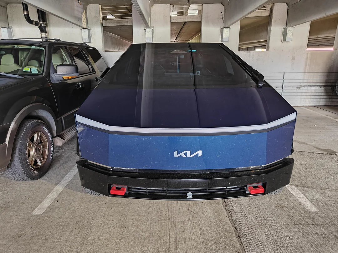 Modré auto Kia futuristického dizajnu zaparkované vedľa čierneho auta v podzemnej garáži.