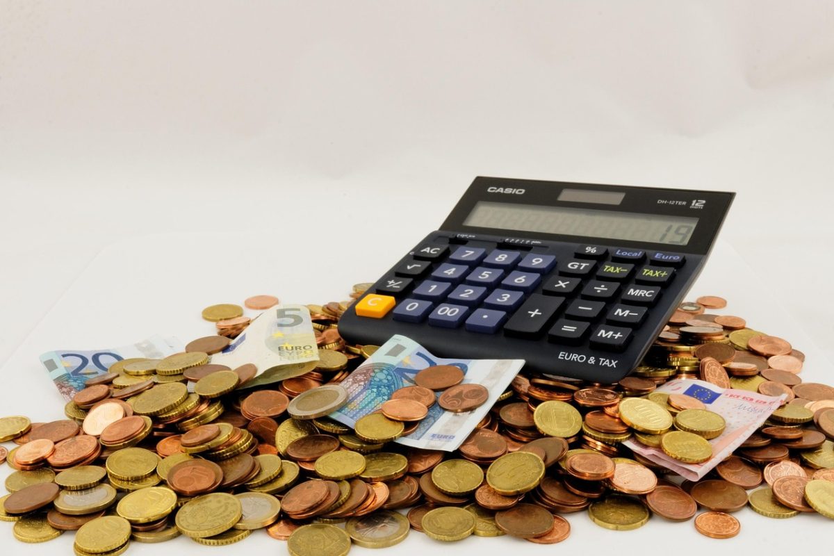 Kalkulačka na hromade euro mincí a bankoviek, financie a výpočet daní.